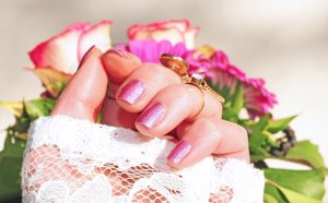 A girl is showing her nail polish in front of flowers