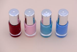 There are four different colors of nail polish on the table