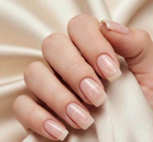 High-gloss glass nails manicure on squoval shaped nails with sheer nude pink polish resting on beige silk fabric, 2026 nail trend style (1)
